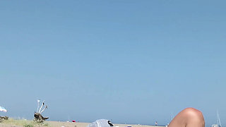 She masturbates her on the naturist beach in public with a voyeur who passes by