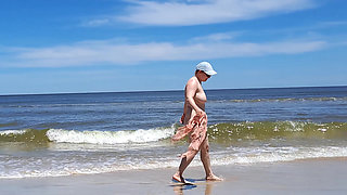 Amateur filming. A nudist plays with waves on the ocean shore.